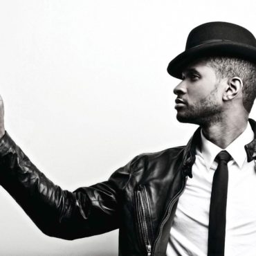 Black and white photo of Usher giving the Ok sign with